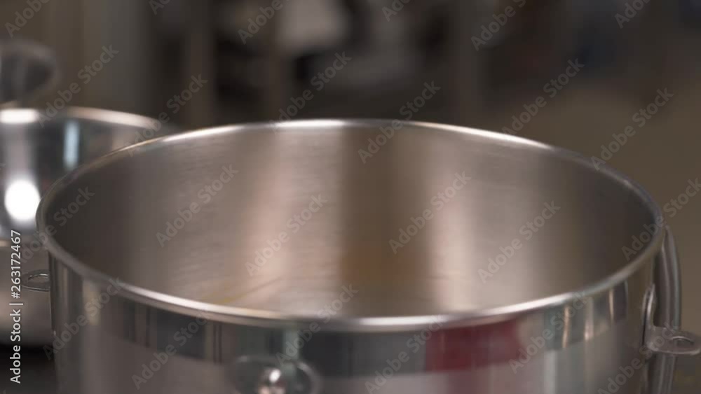 A close-up of a chef adding turmeric powder to the rest of ingredients into food processor bowl. Food preparation concept. Professional bakery