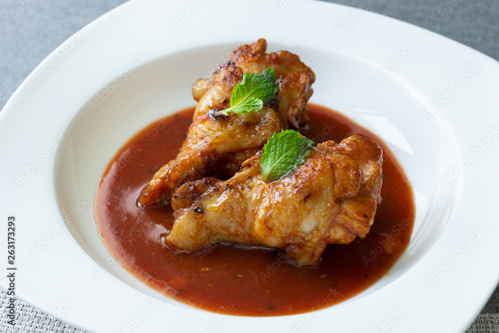 Spicy drumstick or Fried chicken with tomato sauce and black pepper in white dish on concrete table.