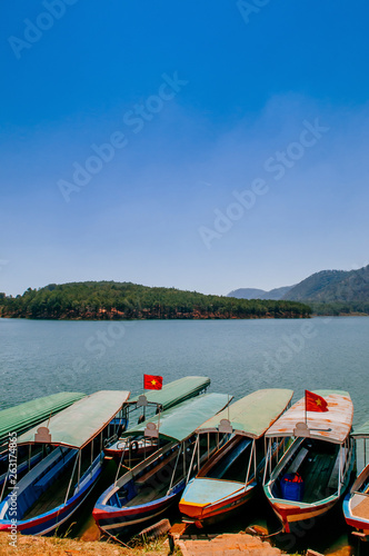 Fototapeta Naklejka Na Ścianę i Meble -  Wooden tourist boats at Tuyen Lam lake or Ho Tuyen Lam in Da Lat - Vietnam with blue sky in spring season