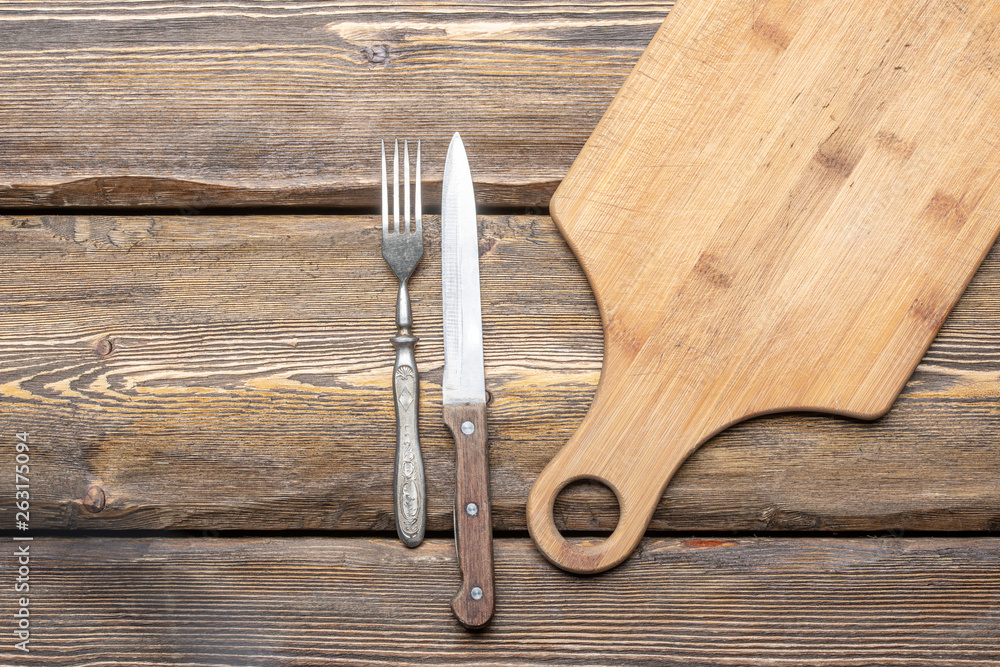 utensils with square candle and vintage cutlery on wooden background, top view 