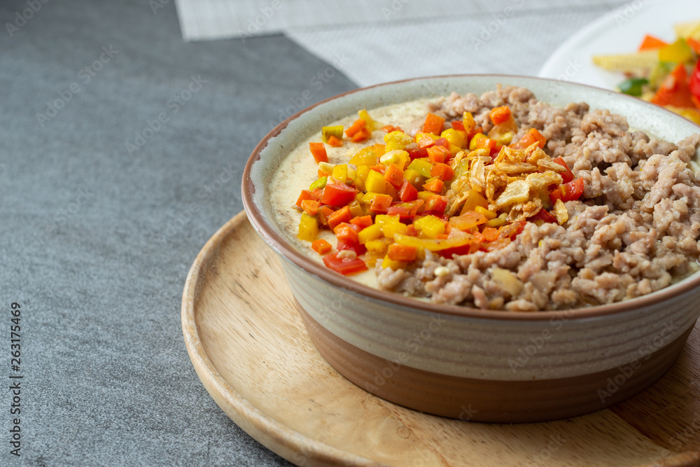 Beaten steamed egg with sweet pepper,carrot and chopped chicken in brown bowl on concrete table. Beaten steamed egg with sweet pepper,carrot and chopped chicken in brown bowl on concrete table.