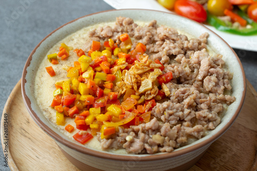 Beaten steamed egg with sweet pepper,carrot and chopped chicken in brown bowl on concrete table.