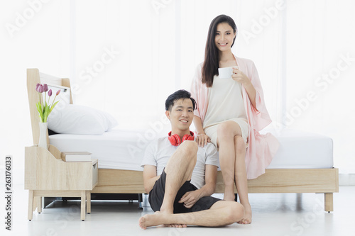 Sexy Asian couple in pajamas sit in bedroom..