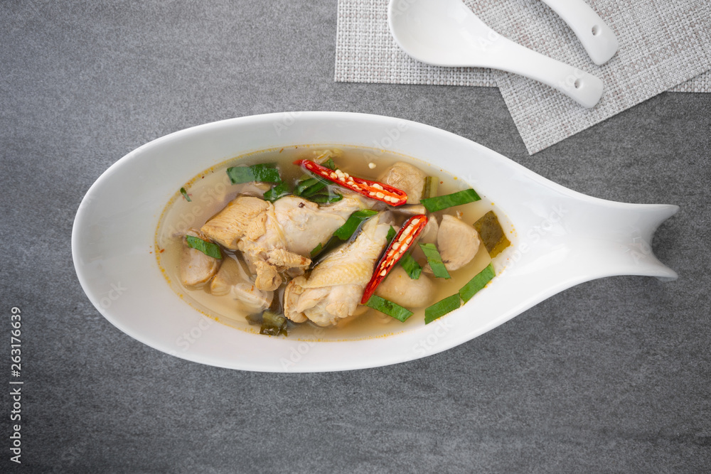 Sour and spicy soup with chicken drumstick in white bowl on concrete table. Sour and spicy soup with chicken drumstick in white bowl on concrete table.