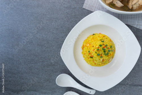 Fried rice with turmeric,carrot,egg and coriander or Yellow fried rice in white dish on concrete table.