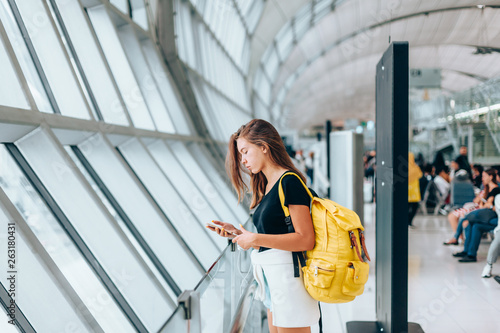 Teen girl waiting for international flight in airport departure terminal photo