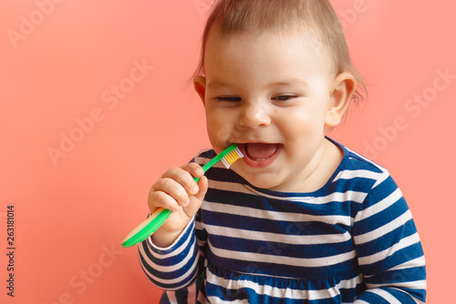 Little beautifulbaby toddler cleaning teeth with child brush on pink background happy face