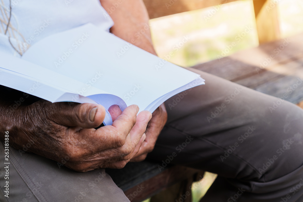 Obraz premium Adult education Learning Studying concept : Happy Asian Elderly retired man sitting reading book at garden home outdoor for learning or relax by self