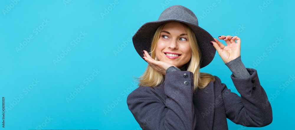 Photo of happy blonde woman in hat on empty blue background.