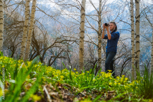 A man shoots a photo in the spring birch forest