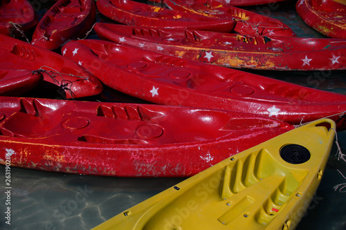 Red and yellow kayaks are floating on a sea