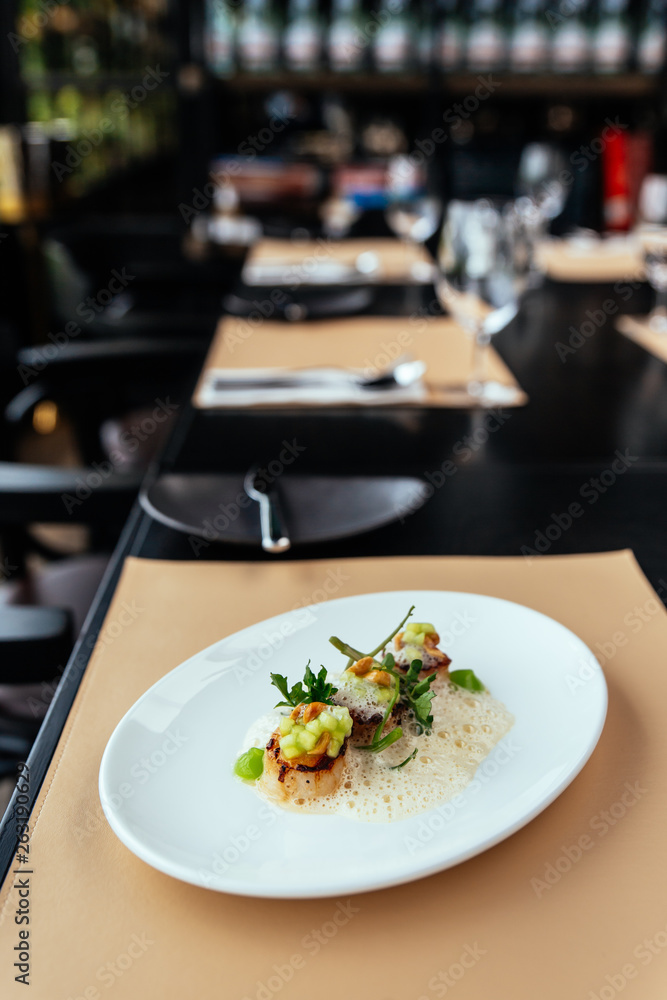Molecular Creative Fine Dining: Hokkaido Scallop with green apple, hazelnut and shellfish veloute. Served in white plate on leather mat. Molecular Creative Fine Dining: Hokkaido Scallop with green apple, hazelnut and shellfish veloute. Served in white plate on leather mat.
