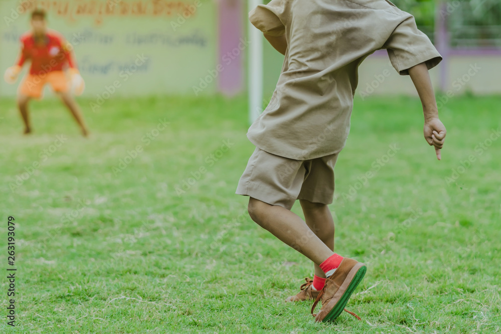 Fototapeta premium Asian boys practice kicking the ball to score goals in the public football field.