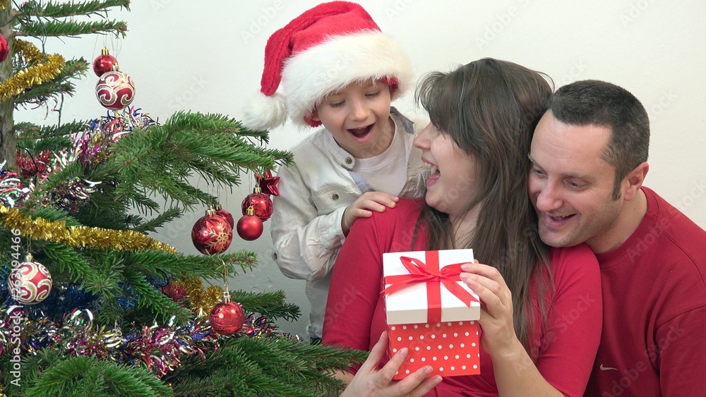 Happy family looking surprised at gift box close Christmas tree, playful child Happy family looking surprised at gift box close Christmas tree, playful child