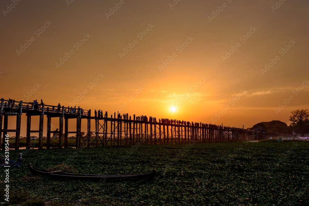 Silhouette of people crossing iconic U-Bein bridge during sunset, Mandalay, Myanmar