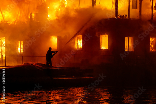 Firefighters spraying high pressure water to burning house. Conflagration. Ukraine.