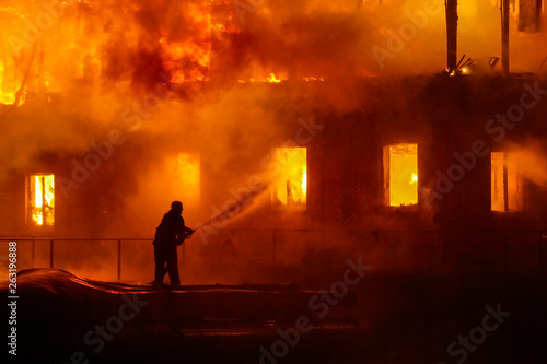 Firefighters spraying high pressure water to burning house. Conflagration. Ukraine.