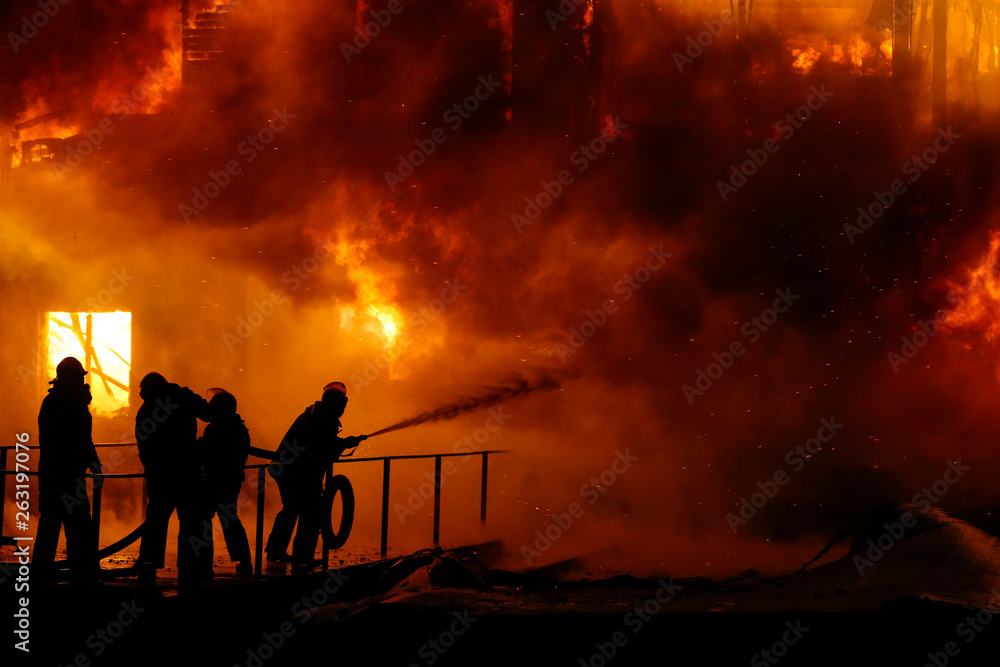 Fototapeta premium Firefighters spraying high pressure water to burning house. Conflagration. Ukraine.