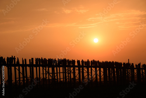 People crossing the longest teak bridge in the world, the iconic wooden U Bein Bridge during sunset, Mandalay, Myanmar