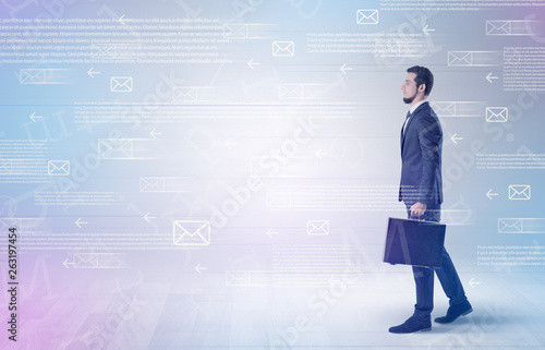 Handsome businessman walking in suit with briefcase on his hand and online communication concept around 