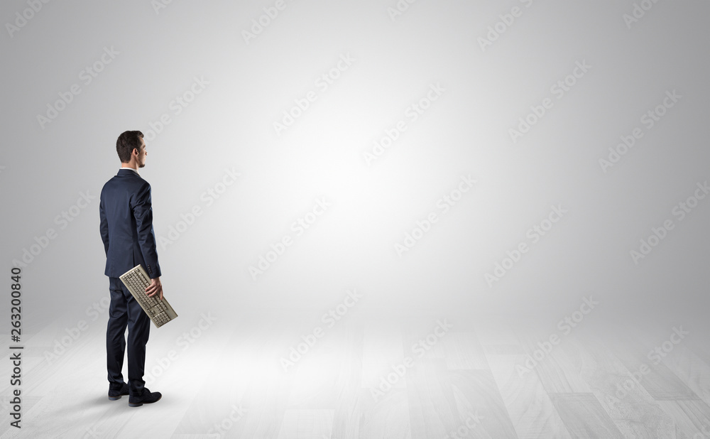 Man standing with his back in an empty room with object in his hand Man standing with his back in an empty room with object in his hand