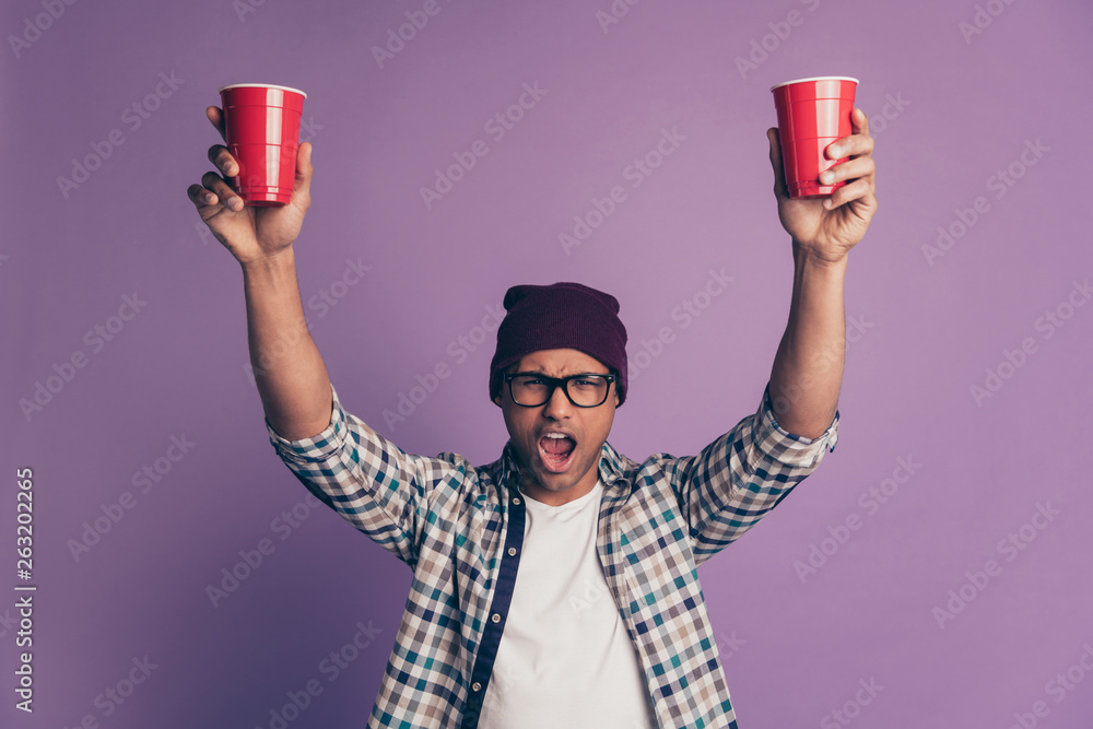 Close up photo portrait of cheerful glad mad drunk carefree in eyeglasses guy holding rising holding in hands palms big bright plastic glasses with beverage isolated violet background Close up photo portrait of cheerful glad mad drunk carefree in eyeglasses guy holding rising holding in hands palms big bright plastic glasses with beverage isolated violet background