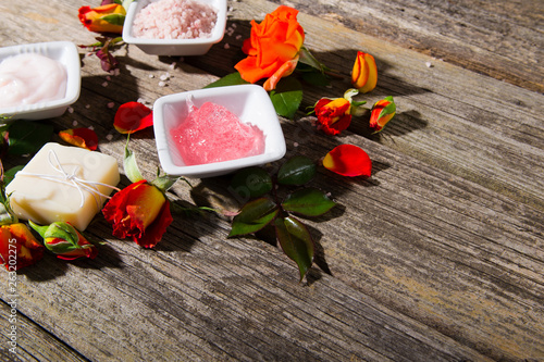 beauty product samples with rose flowers and buds on weathered old wooden table