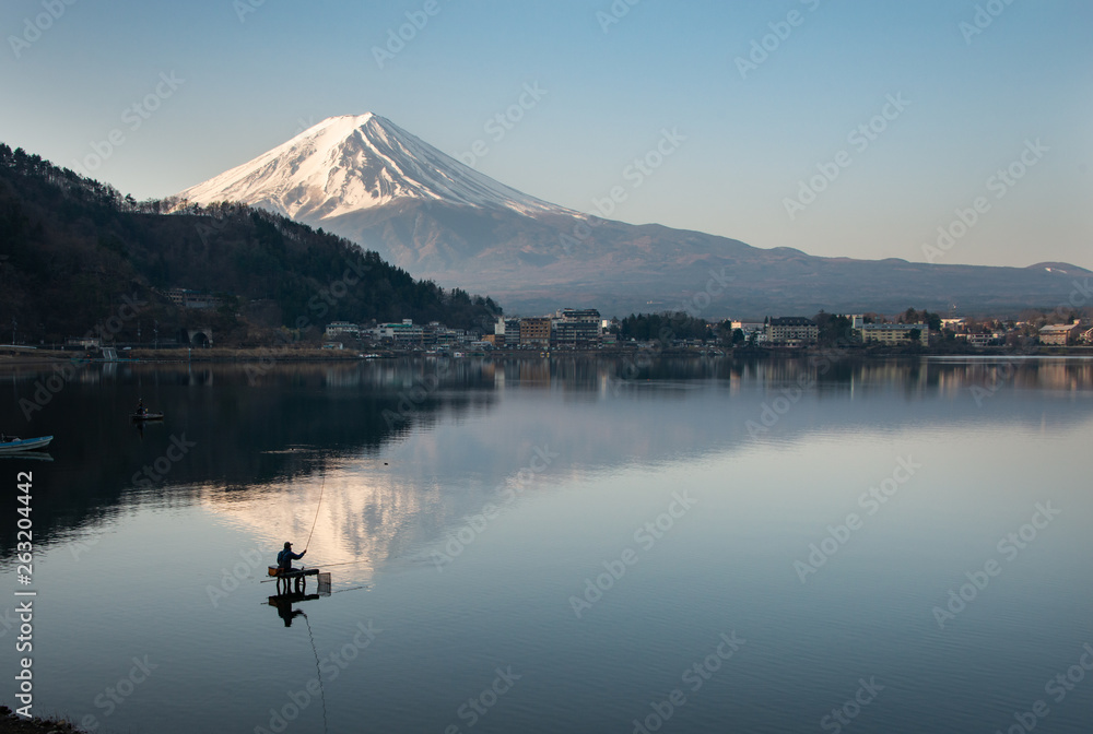 View of Mount Fuji reflected in the lake Kawaguchiko with fishermen out fishing on the lake
