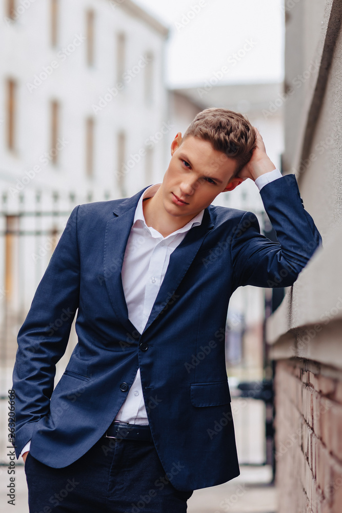 young stylish guy with a monumental face walks in a cool city near the wooden and stone walls young stylish guy with a monumental face walks in a cool city near the wooden and stone walls