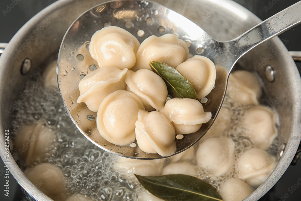 Closeup of dumplings on skimmer over stewpan with boiling water. Home cooking Closeup of dumplings on skimmer over stewpan with boiling water. Home cooking