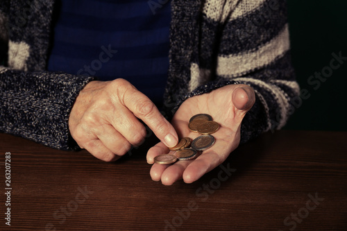 Poor senior woman with coins at table, closeup