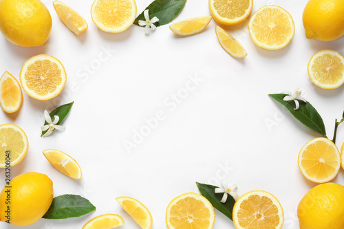 Frame made of lemons, leaves and flowers on white background, top view with space for text. Citrus fruits