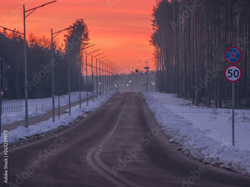 Asfaltowa droga zimą o wschodzie słońca.