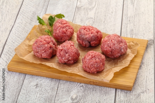 Raw meatball over wooden background