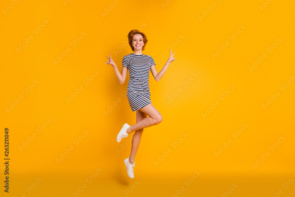 Full length body size view portrait of nice cool lovely charming attractive cheerful cheery optimistic girl jumping up in air showing double v-sign isolated over bright vivid shine yellow background Full length body size view portrait of nice cool lovely charming attractive cheerful cheery optimistic girl jumping up in air showing double v-sign isolated over bright vivid shine yellow background
