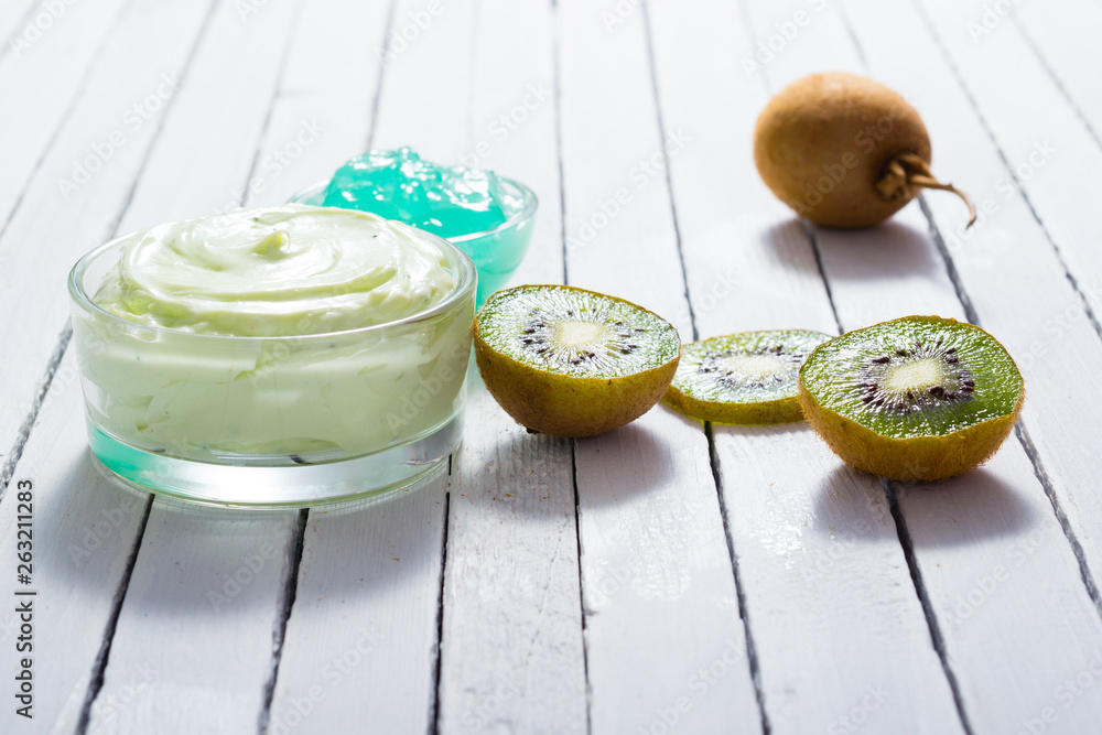 moisturizer and anti aging gel with kiwi on white wooden table moisturizer and anti aging gel with kiwi on white wooden table