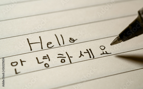 Beginner Korean language learner writing Hello word Annyeonghaseyo in Korean characters on a notebook photo