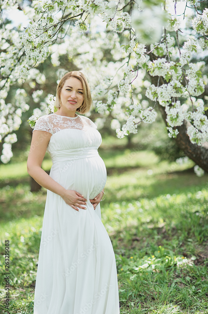 Spring mood, beautiful pregnant woman smell flowering cherry tree, enjoying nature, white floral garden. Spring mood, beautiful pregnant woman smell flowering cherry tree, enjoying nature, white floral garden.