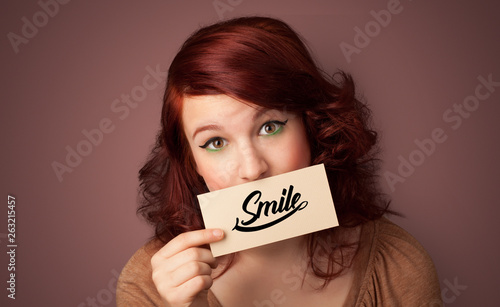 Person holding card with smile in front of her mouth 