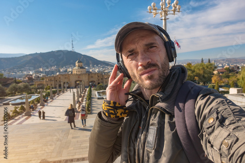 Male tourist in headphones on the territory of Tsmind Sameba (Holy Trinity) Cathedral in Tbilisi. photo