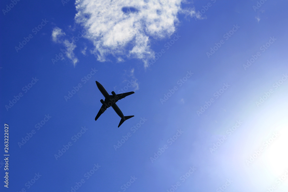 Silhouette of a jetliner flying in a blue sky where the sun shines Silhouette of a jetliner flying in a blue sky where the sun shines