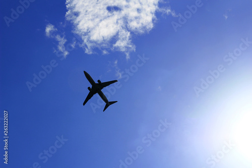 Silhouette of a jetliner flying in a blue sky where the sun shines