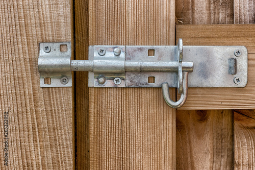 A steel bolt latch on a wooden gat close up