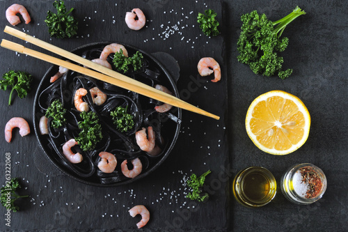 Black noodles with shrimp and greens. Food trends. Black food.