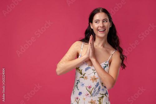 Portrait of a pretty young woman in a light dress standing on pink background in studio. People sincere emotions. © nazarovsergey