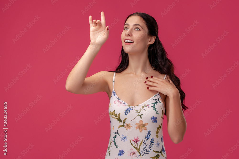 Portrait of a pretty young woman in a light dress standing on pink background in studio. People sincere emotions. Portrait of a pretty young woman in a light dress standing on pink background in studio. People sincere emotions.