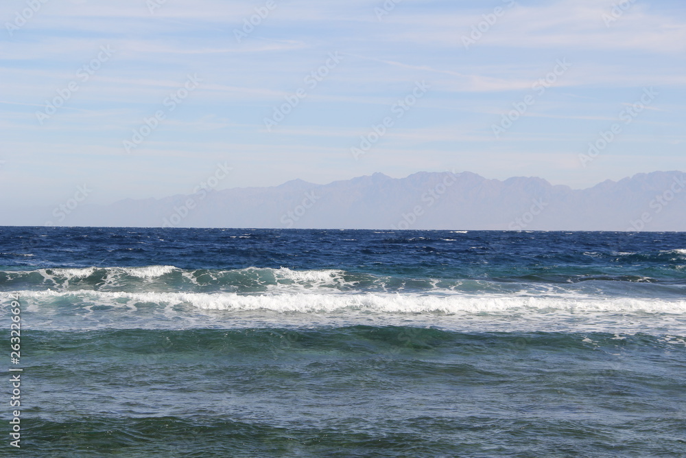 Sea with waves and mountains on the horizon