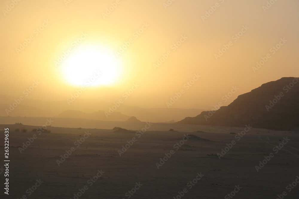 Sunset in the desert with dunes and rocky mountains