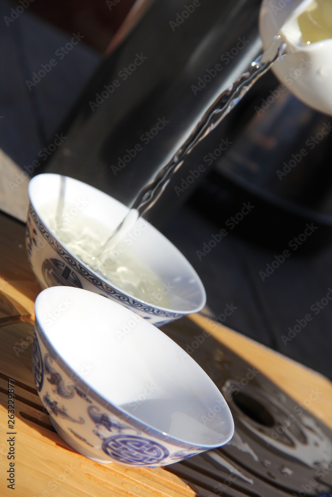 Pouring tea into porcelain cups in a tea ceremony
