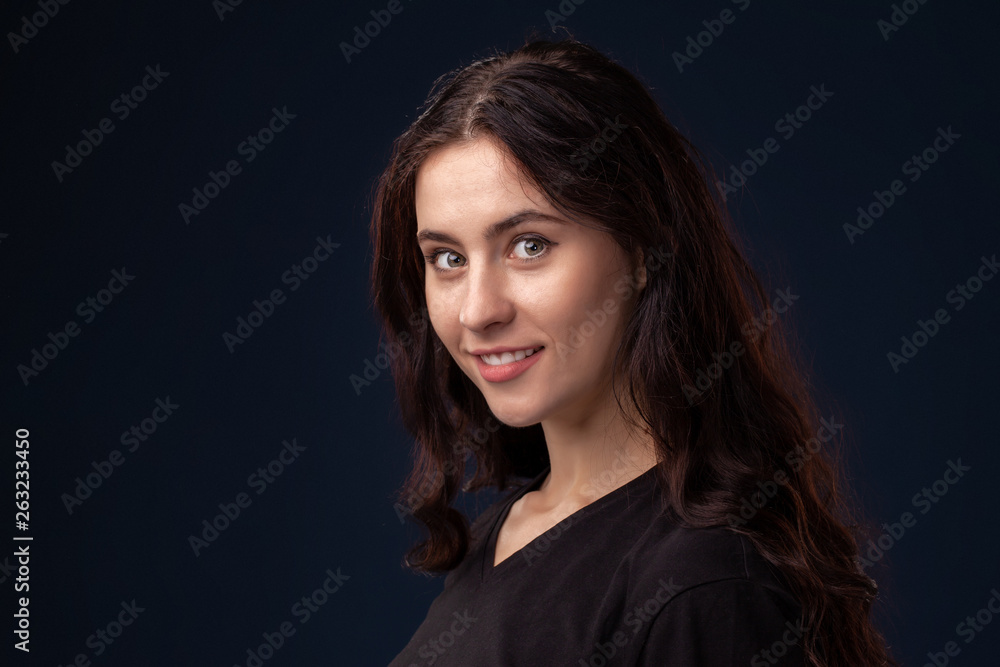 Close-up portrait of a beautiful brunette with curly hair and professional make-up posing on a black background. Close-up portrait of a beautiful brunette with curly hair and professional make-up posing on a black background.
